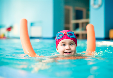 Young child swimming with pool noodle